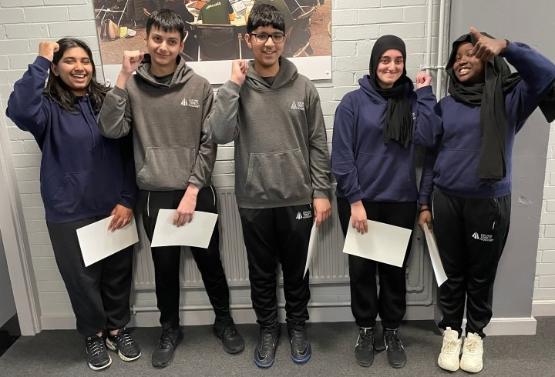 Five students stand up and celebrate winning an event at the university