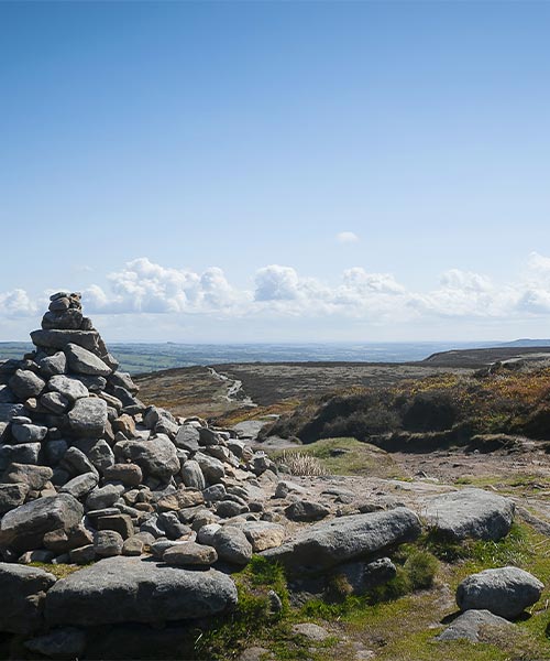 A scenic image of large fields with a stack of rocks in the foreground.