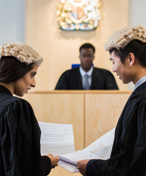 Students wearing gowns and wigs using the mock court room