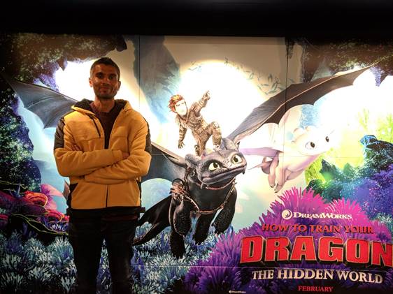 Ravi Kamble Govind standing next to a poster of How to Train your Dragon.