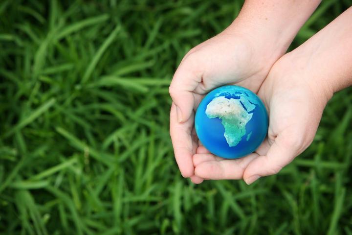 Hands holding a globe showing africa with green grass background
