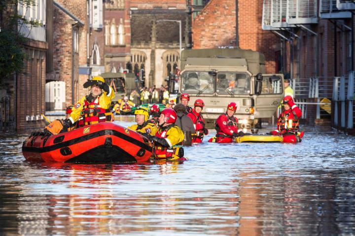 Image showing flood in town with people being evacuated in boats