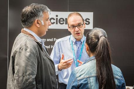 An academic speaking to a prospective student and their parent at a University Open Day.