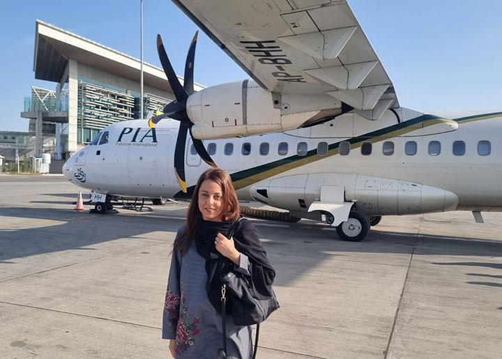 Dr Samina Karim standing in front of a plane having arrived at Sukkur Airport, Pakistan