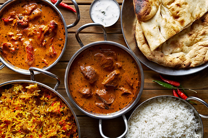 A selection of curries in mental dishes with rice and breads