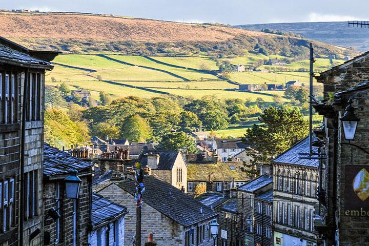 A view over the tops of houses, looking onto green fields in Haworth.