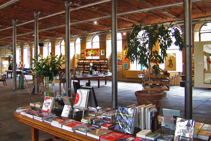 Inside the ground floor of Salts Mill, showing a display of books for sale, and artwork.