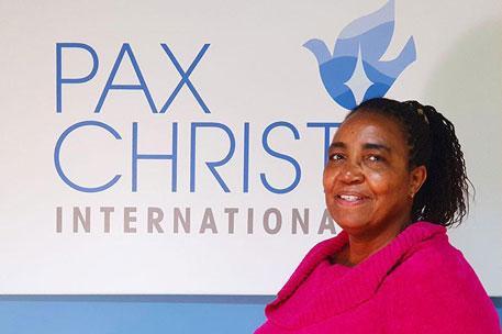 Teresia Wamayu Wachira standing in front of a Pax Christi International logo