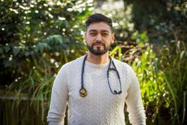 MPAS graduate Mobashar Rashid standing in the Peace Garden with his stethoscope round his neck