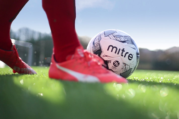 A close-up of a shoe kicking a football
