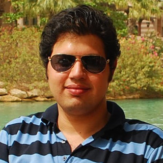 Headshot of Fahim next to a river with trees and stone buildings in the distance.