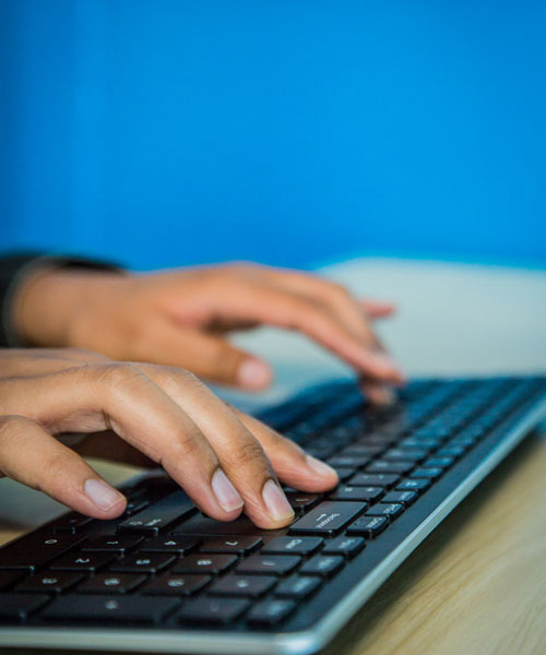 Two hands typing on a computer keyboard.