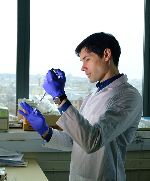 A scientist in a lab adding liquid to a test tube