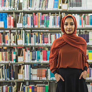 A student stood in front of a bookshelf in the library.