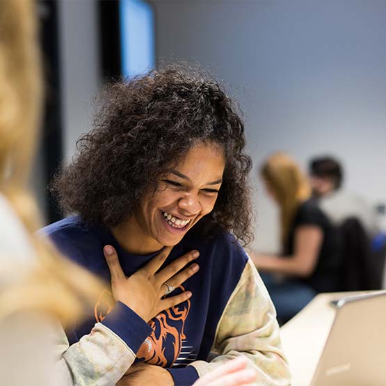 A student laughing with their hand on their chest.