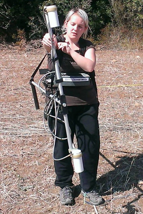 Kayt Armstrong in a field with Archaeological surveying equipment Kayt Armstrong in a field with Archaeological surveying equipment