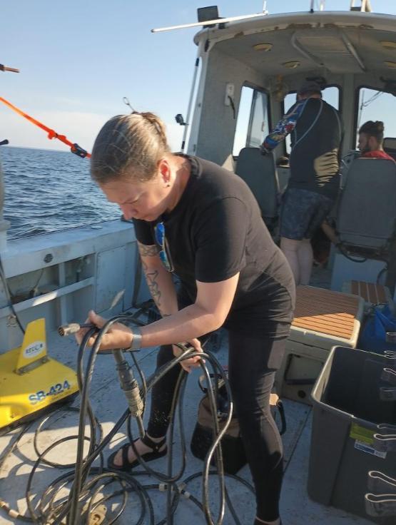 A university staff member leaning over while carrying out work on a boat A university staff member leaning over while carrying out work on a boat