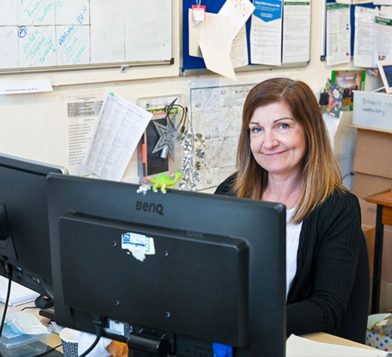A woman is sat working at her desktop computer.
