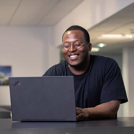 A student smiling at their laptop.