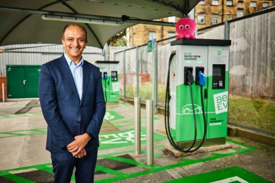 A person dressed in a suit stands next to an electric vehicle charging point A person dressed in a suit stands next to an electric vehicle charging point
