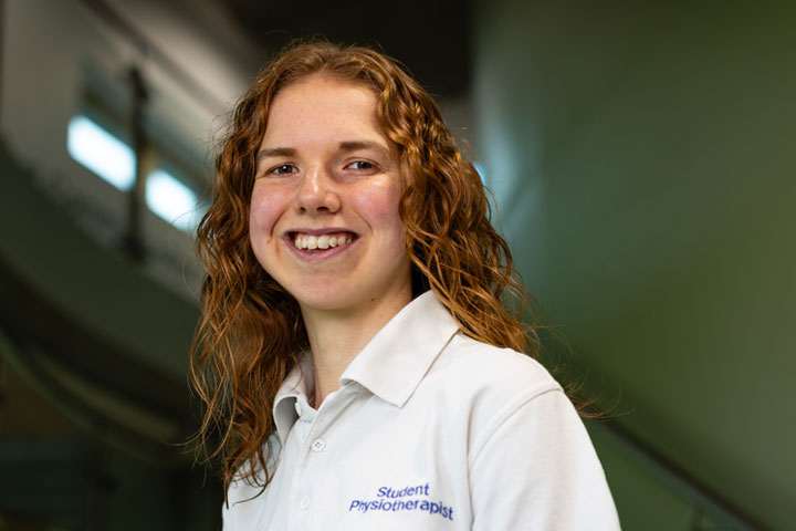 A student wearing a physiotherapy uniform smiling at the camera