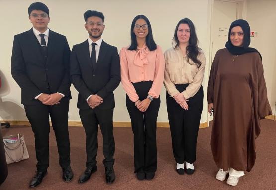 Five students in smart business-type dress stand up for photos Five students in smart business-type dress stand up for photos