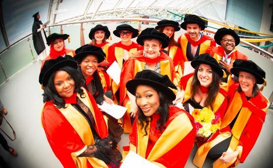 A group of graduates stare into the camera wearing gowns and hats A group of graduates stare into the camera wearing gowns and hats
