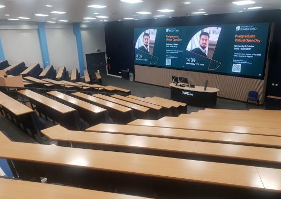 Lecture theatre with desks leading down to screen Lecture theatre with desks leading down to screen