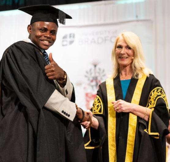 Professor Shirley Congdon shakes the hand of a graduate on stage Professor Shirley Congdon shakes the hand of a graduate on stage