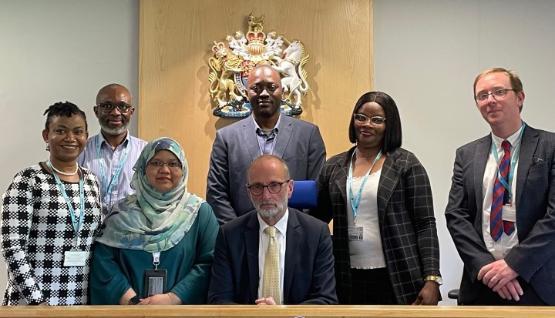 A group of university staff stood up in a courtroom behind a seated judge A group of university staff stood up in a courtroom behind a seated judge