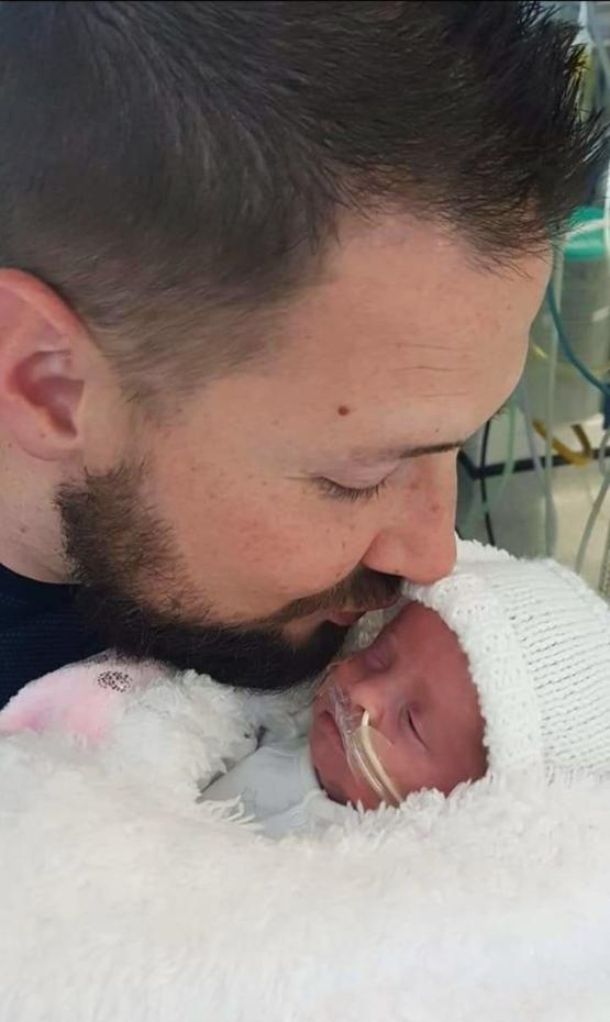 a person kissing a baby on their head while they are in hospital a person kissing a baby on their head while they are in hospital
