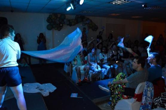A performer on stage during a show holding a bed sheet out towards an audience A performer on stage during a show holding a bed sheet out towards an audience