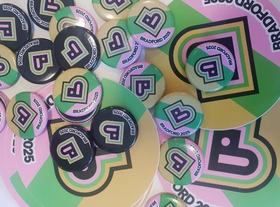 Bradford City of Culture 2025 badges laid on a table Bradford City of Culture 2025 badges laid on a table