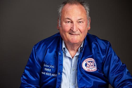Close up photo of a person wearing a blue bomber type jacket smiling at the camera Close up photo of a person wearing a blue bomber type jacket smiling at the camera