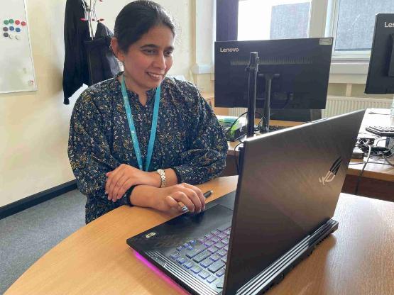Staff member sat down at desk on laptop Staff member sat down at desk on laptop