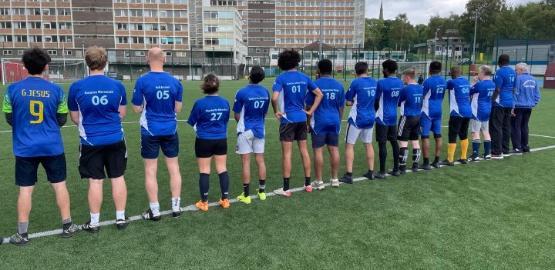 A number of people dressed in football kit line up on the halfway line of the pitch with their backs to the camera for a photograph A number of people dressed in football kit line up on the halfway line of the pitch with their backs to the camera for a photograph