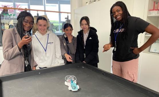 Five students stood around a table in a lab looking at a model car Five students stood around a table in a lab looking at a model car
