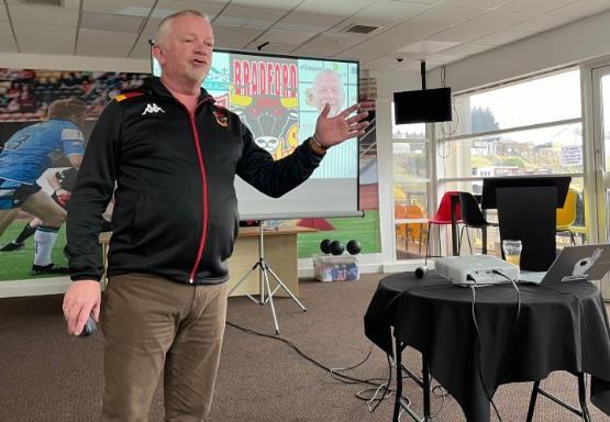 Person in tracksuit top stands up to give guest lecture at sports ground Person in tracksuit top stands up to give guest lecture at sports ground