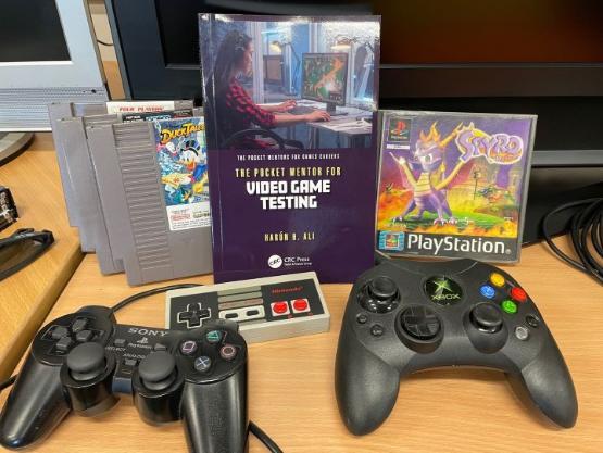 A book surrounded by video games console joypads and video game boxes A book surrounded by video games console joypads and video game boxes