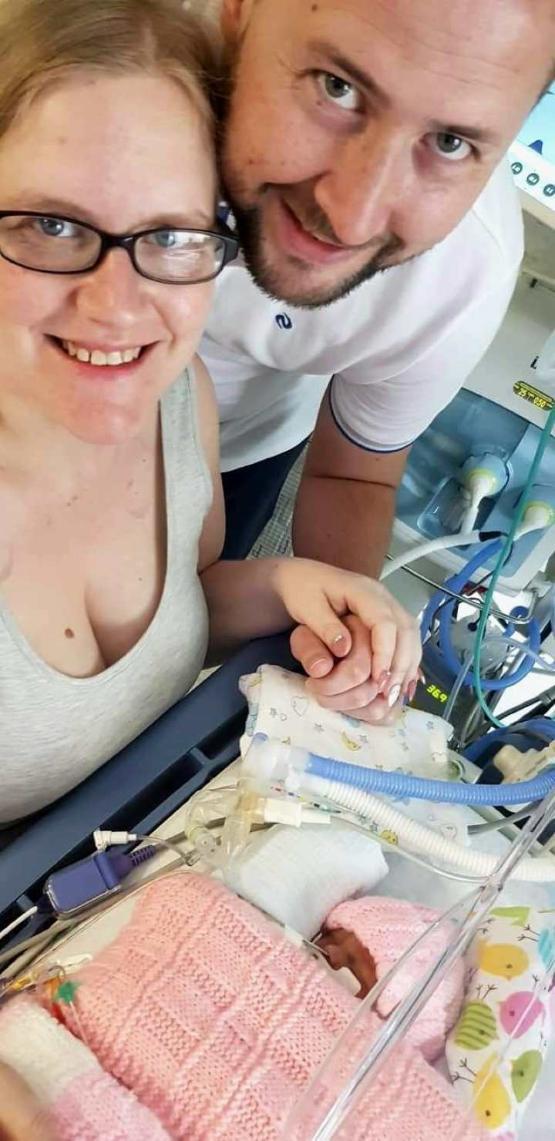 Two people standing up with baby in front of them in a hospital Two people standing up with baby in front of them in a hospital