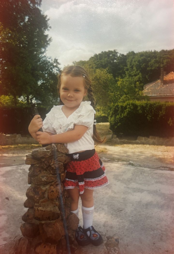 A small girl dressed in a costume in front of a woodland scene A small girl dressed in a costume in front of a woodland scene