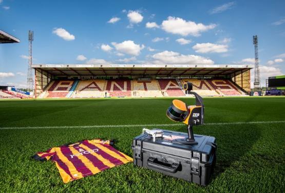 A football shirt lies on the grass touchline of a football pitch next to a box with a drone on top of it inside an empty football stadium A football shirt lies on the grass touchline of a football pitch next to a box with a drone on top of it inside an empty football stadium