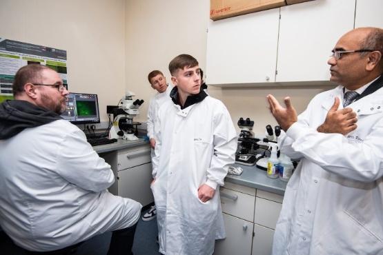 three people in science lab standing up wearing white coats three people in science lab standing up wearing white coats