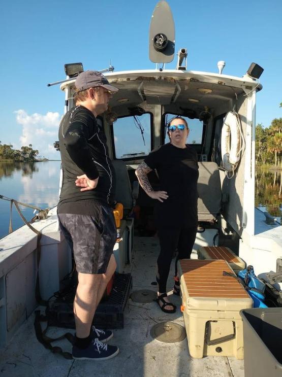 Two university staff stood up on a boat in the USA with a blue sky behind them Two university staff stood up on a boat in the USA with a blue sky behind them