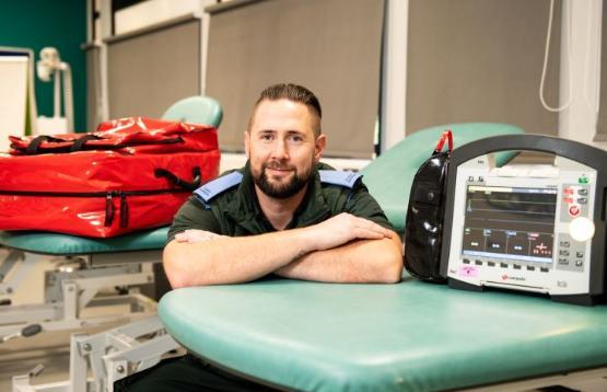 Student sat down with arms folded in front of them next to medical equipment Student sat down with arms folded in front of them next to medical equipment