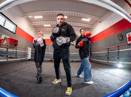 Two students in a boxing ring with professional boxer Tasif Khan Two students in a boxing ring with professional boxer Tasif Khan