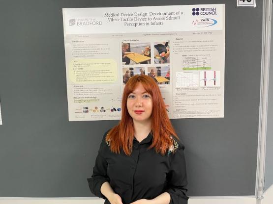 A student smiles for a photo at a poster event