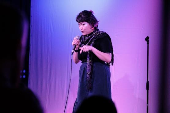 A person stands up in front of a curtain holds a microphone and gives a stand-up comedy show A person stands up in front of a curtain holds a microphone and gives a stand-up comedy show