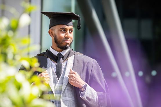 A student posing outside of Richmond Building in a suit and graduation gown and cap. A student posing outside of Richmond Building in a suit and graduation gown and cap.