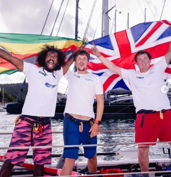 Three graduates dressed in T-shirt and shorts celebrate on a boat holding the United Kingdom and Zimbabwe flags behind them Three graduates dressed in T-shirt and shorts celebrate on a boat holding the United Kingdom and Zimbabwe flags behind them